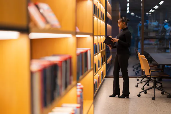 Black woman looking at book in library