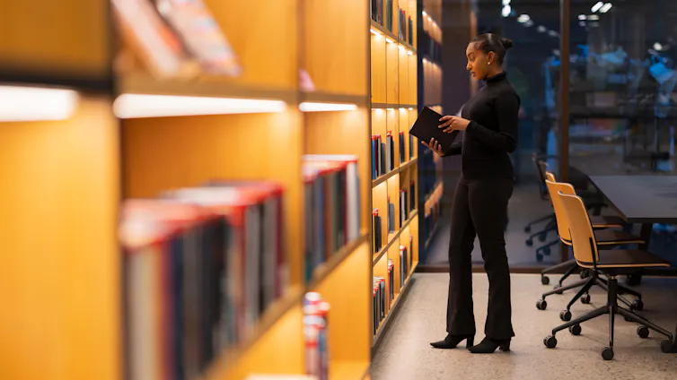 Black woman looking at book in library