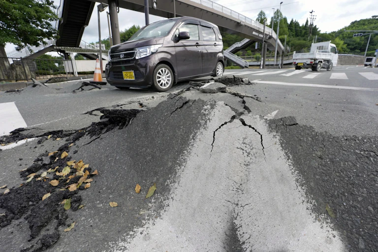 Una carretera levantada con grietas y algunos coches