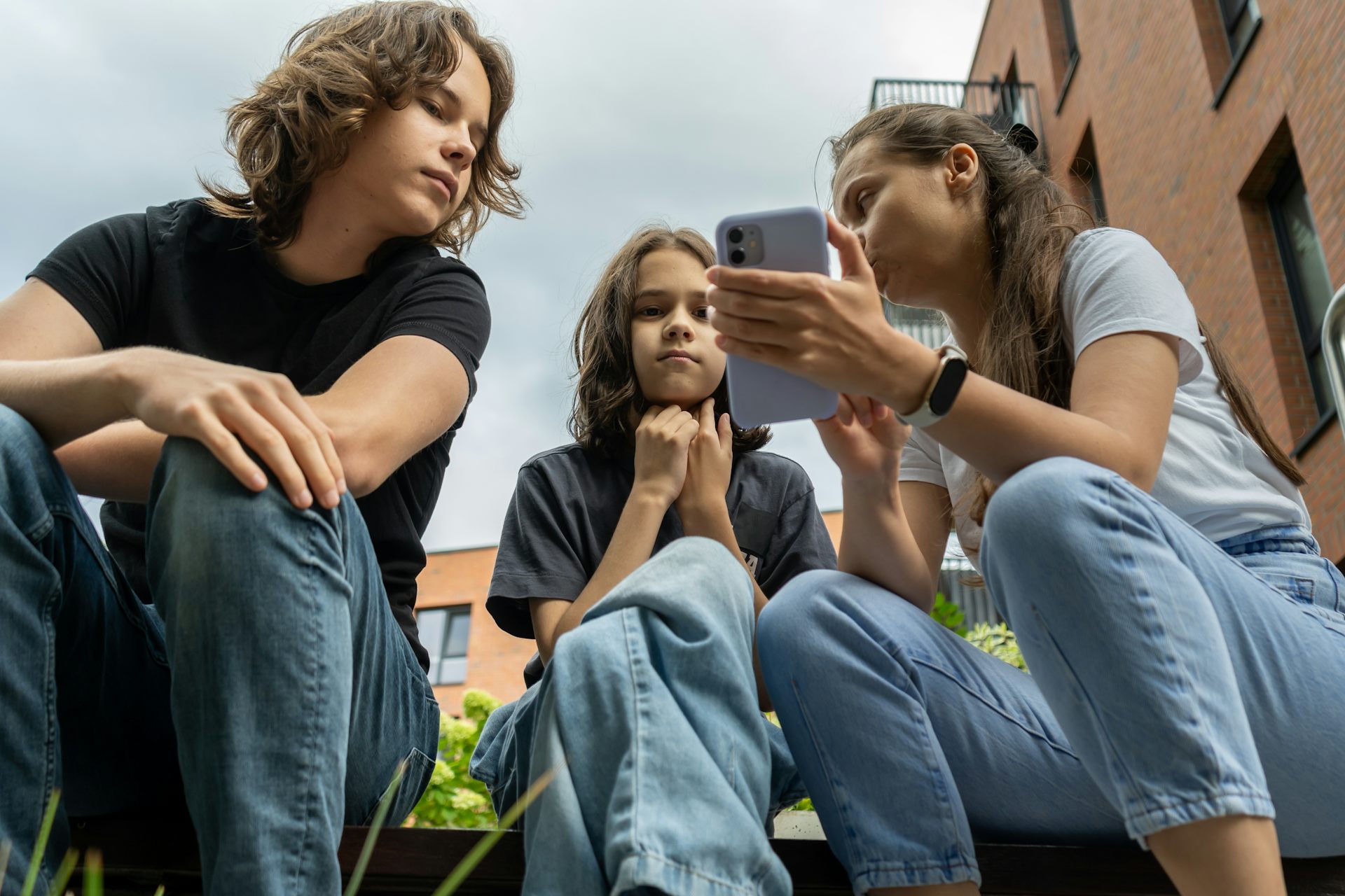 Une mère et ses enfants regardent un smartphone.