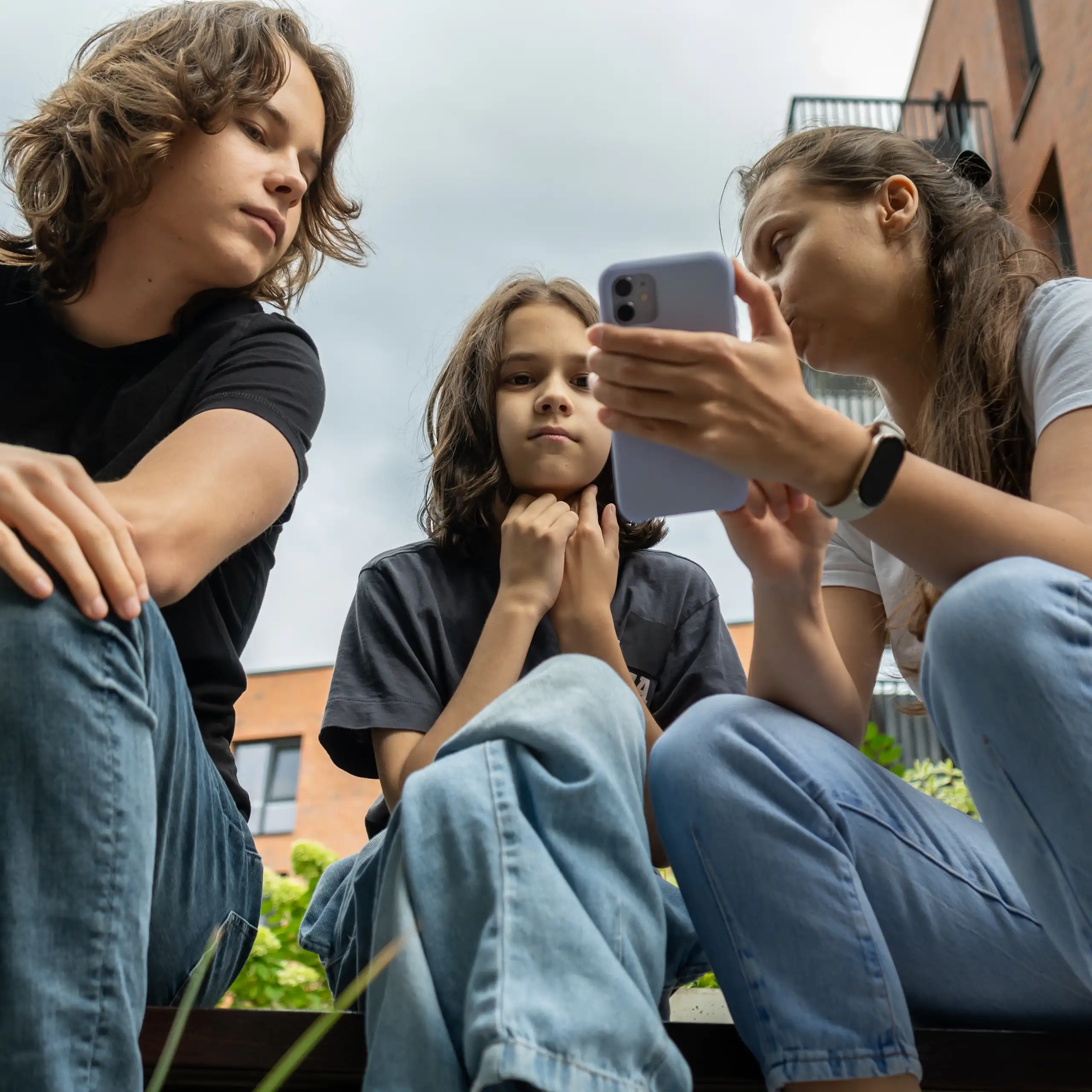 Une mère et ses enfants regardent un smartphone.