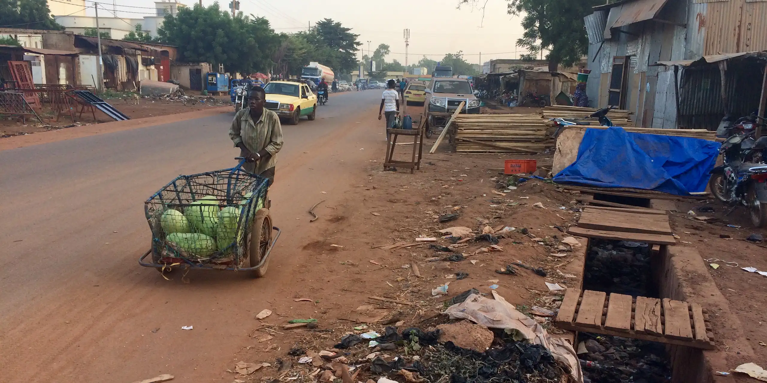 Un jeune garçon pousse une carriole en fer contenant une cargaison de pastèques.