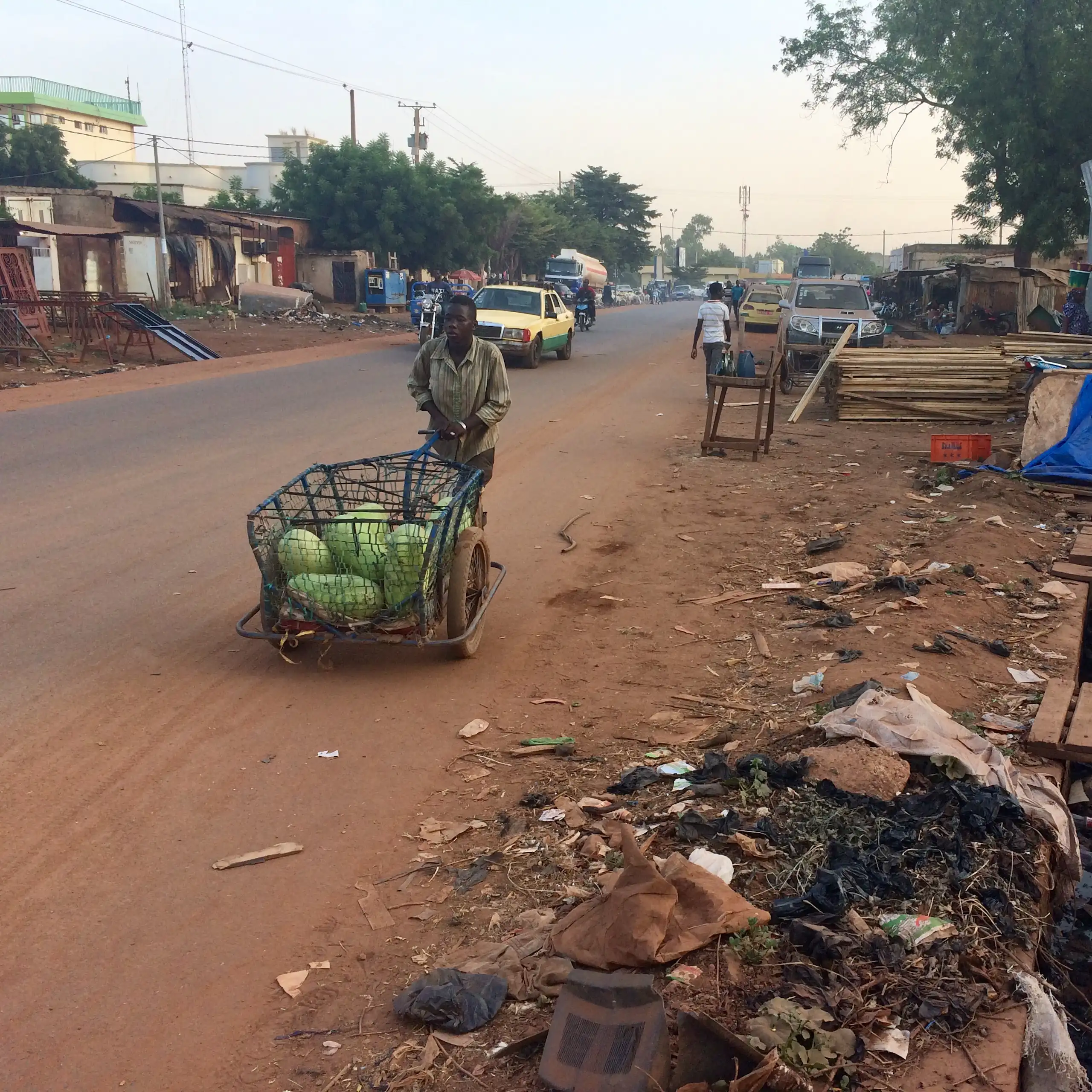 Un jeune garçon pousse une carriole en fer contenant une cargaison de pastèques.