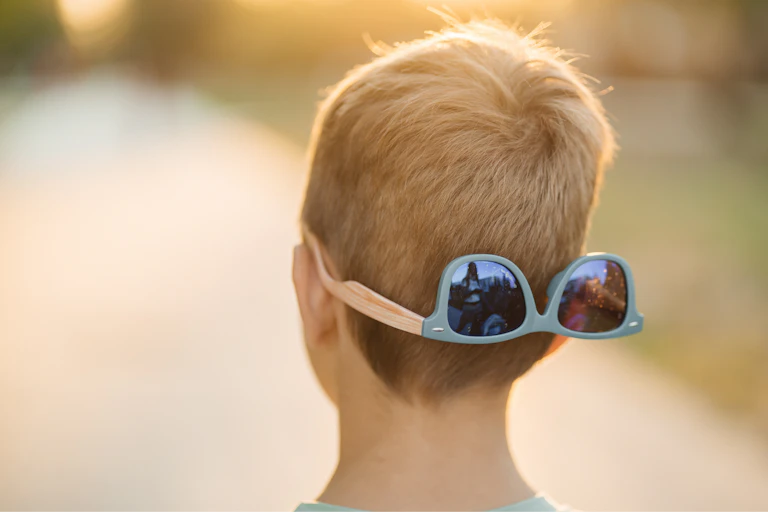 View from behind of a child's head with sunglasses on the back.
