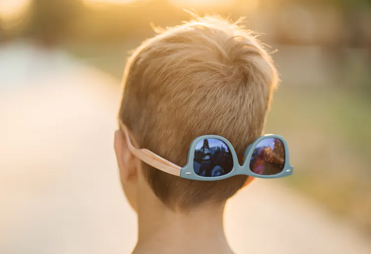 View from behind of a child's head with sunglasses on the back.