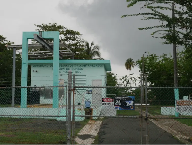 A small square building behind a rusty gate.