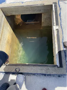 An open box in the ground with water inside.