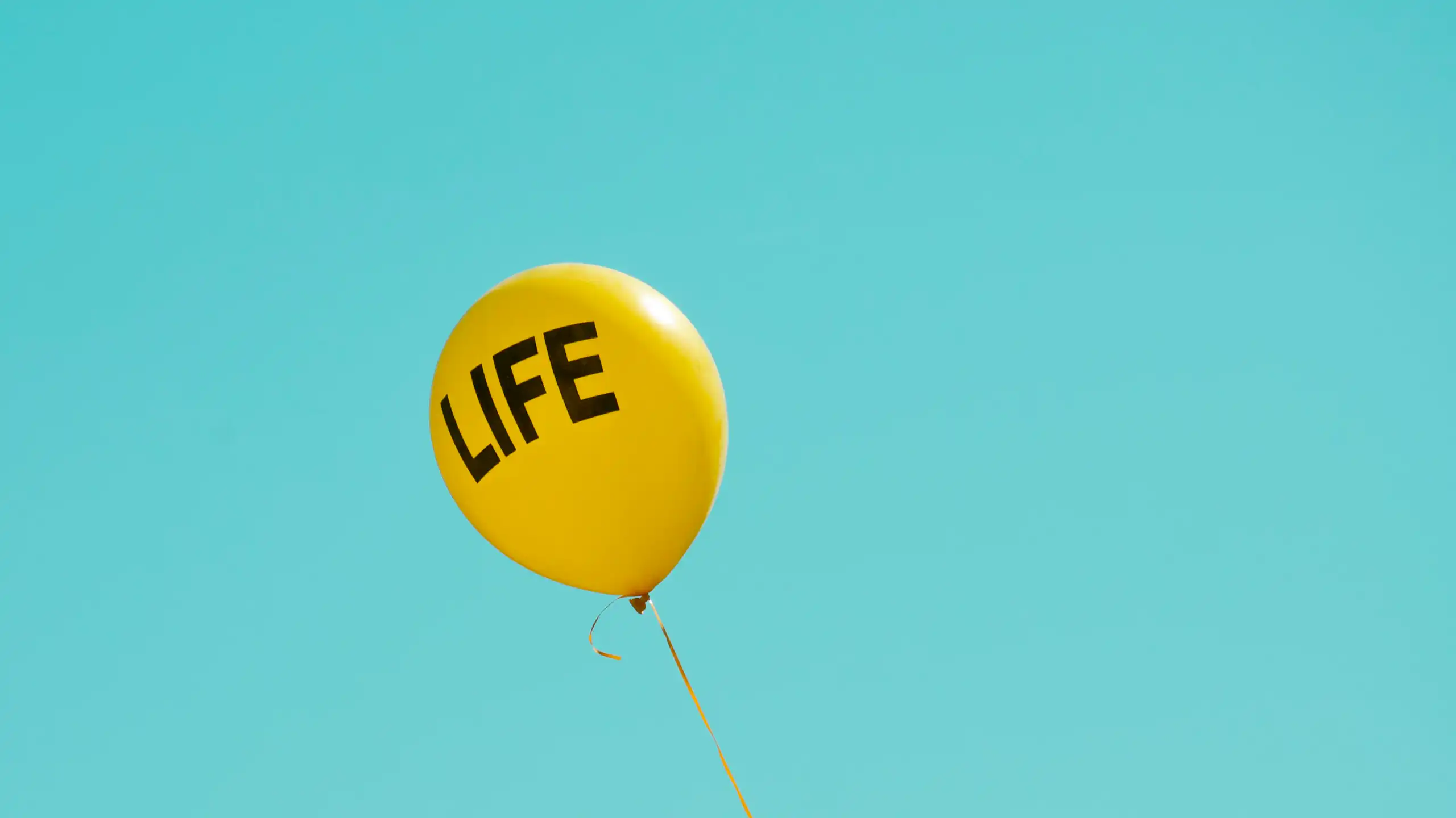 A yellow balloon reading LIFE in a clear blue sky