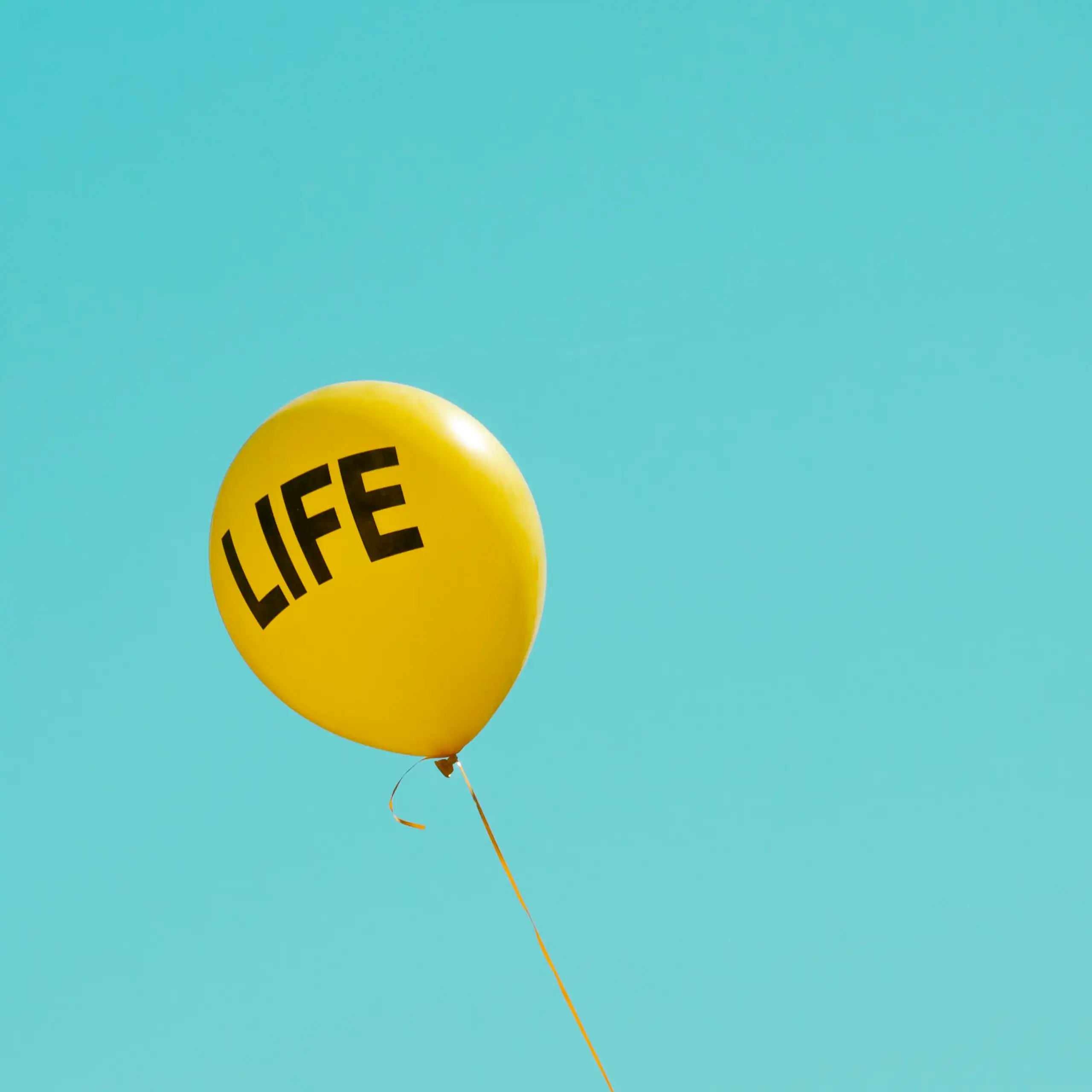 A yellow balloon reading LIFE in a clear blue sky