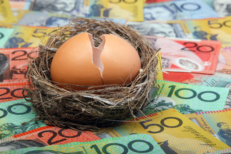 A pile of cash notes with a nest and a cracked open egg in the nest