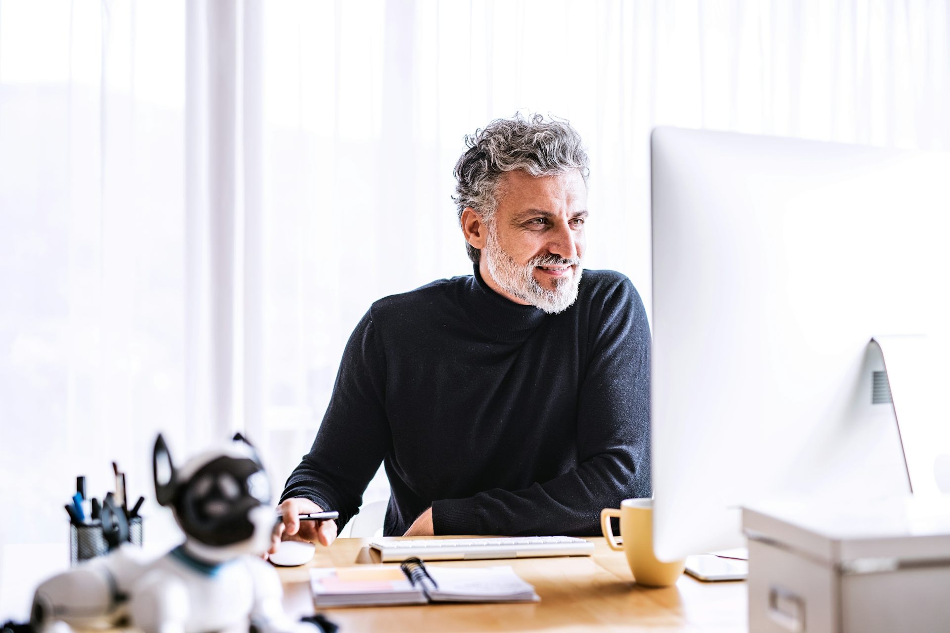 Un homme, souriant, travaille à son ordinateur.