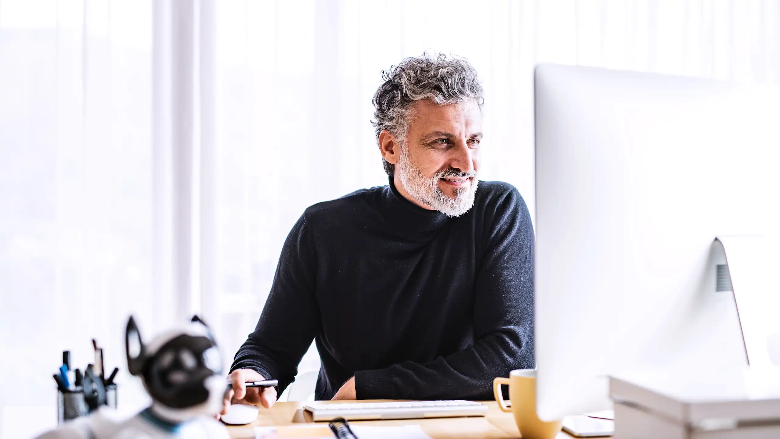 Un homme, souriant, travaille à son ordinateur.