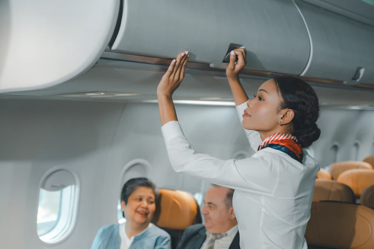 A flight attendant closing an overhead locker.