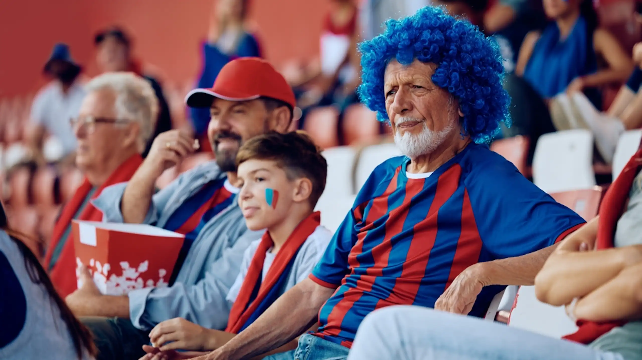 Three football fans of different ages watching a match in the stadium