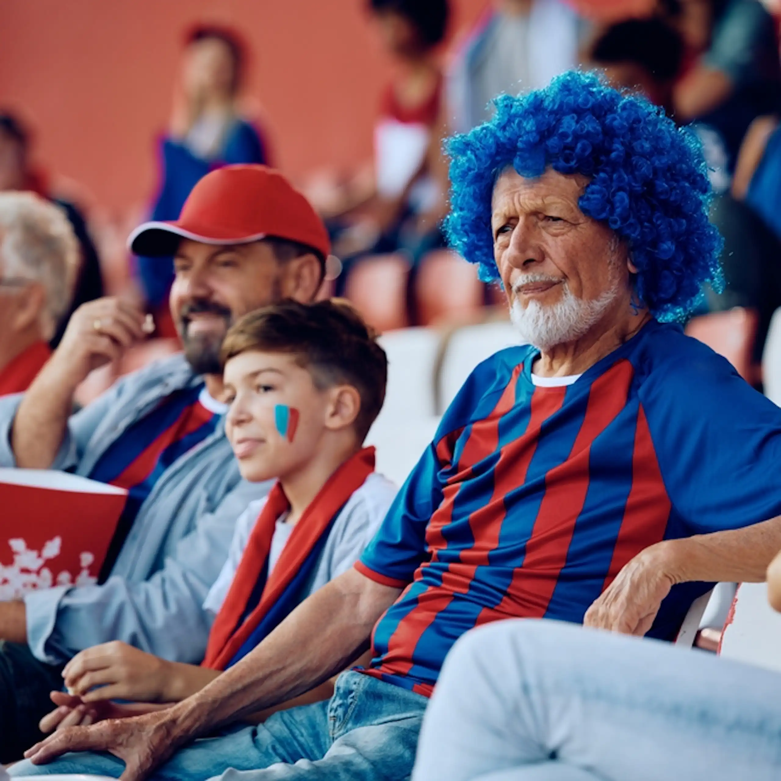 Three football fans of different ages watching a match in the stadium