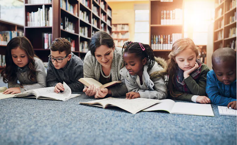 Children and teacher with books on library floor for reading, learning and teaching.