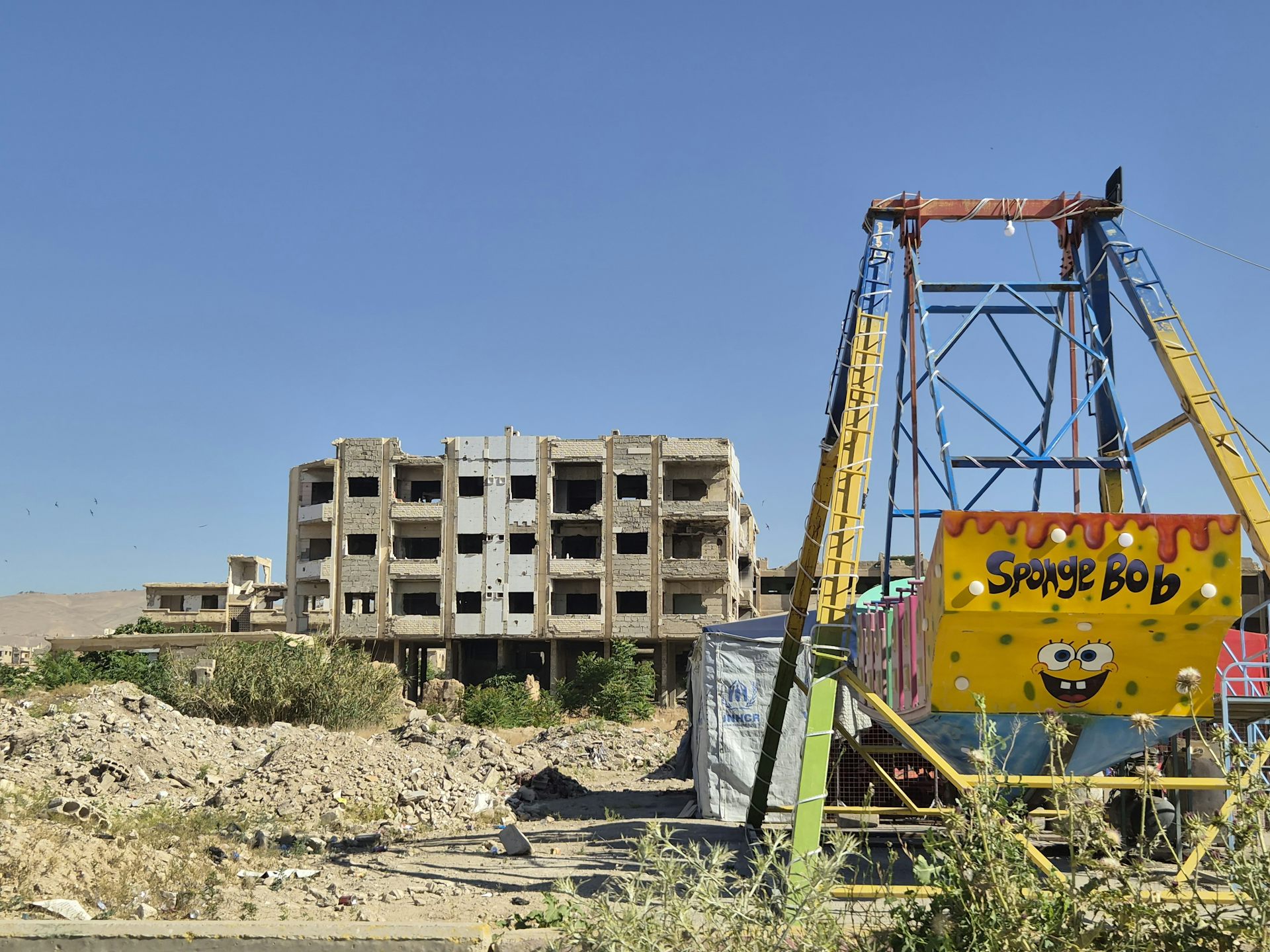 Broken down playground amid city ruins.