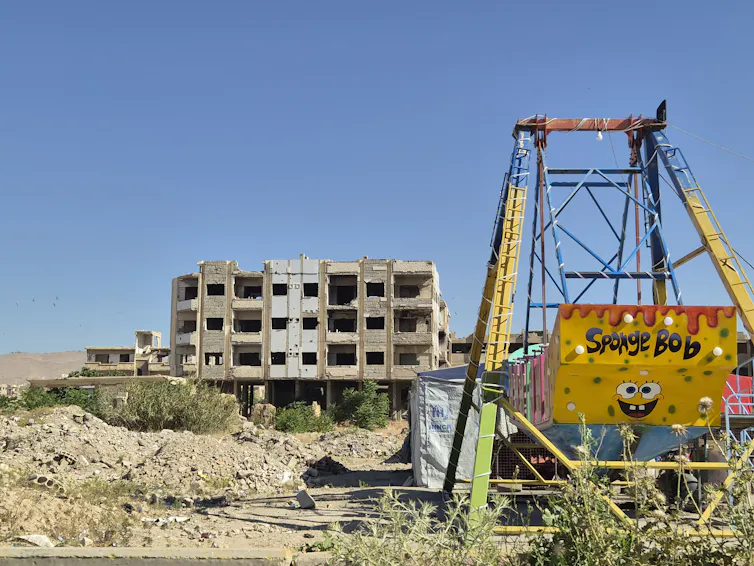 Broken down playground amid city ruins.