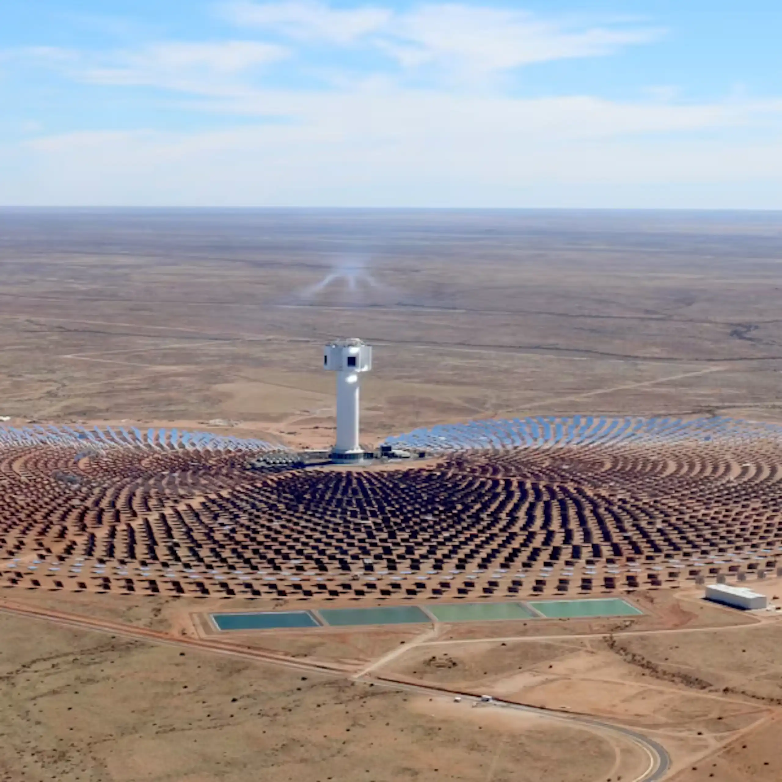 A concentrating solar plant in the middle of a desert - circles of solar panels around a massive central tower