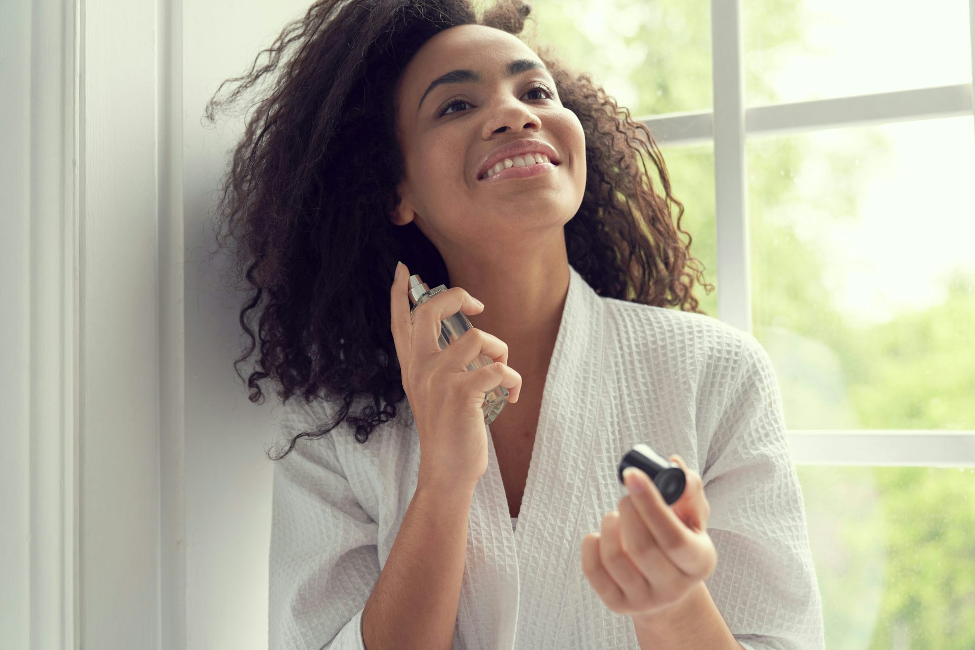 Une femme vaporise du parfum sur son cou