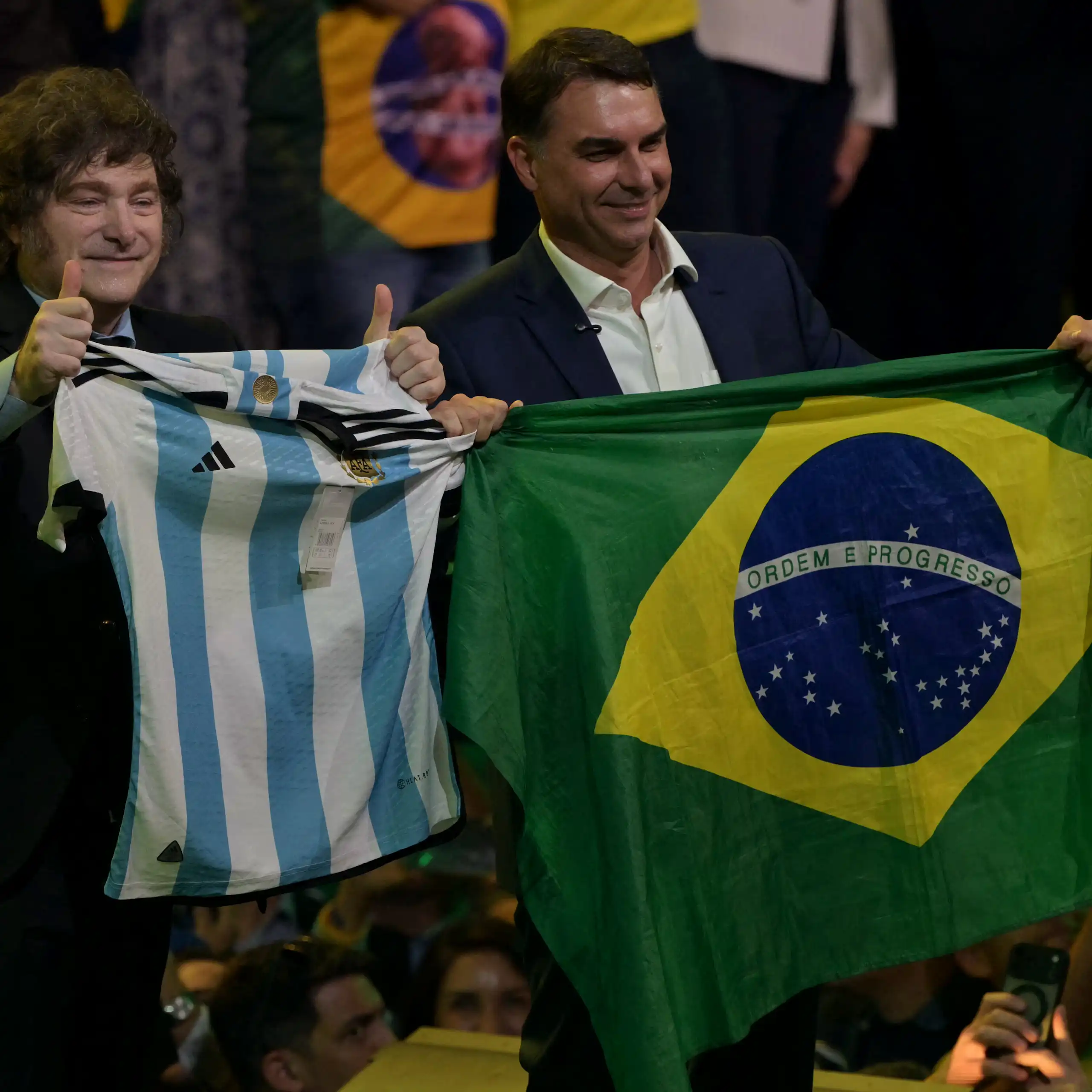 Milei et Falvio Bolsonaro sur la scène brandissent chacun le drapeau respectif de leur pays.