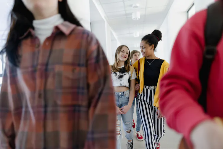 Two girls walk down a school hallway