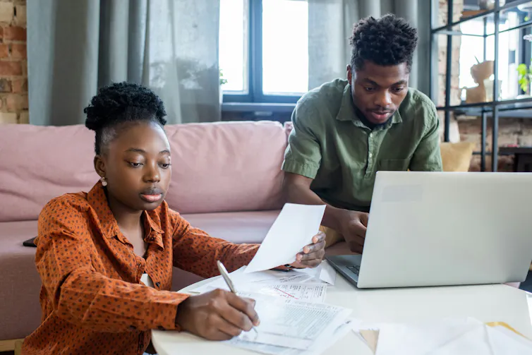 Two people review documents in a living room