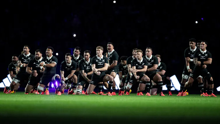 All Blacks team on the field under lights performing the haka