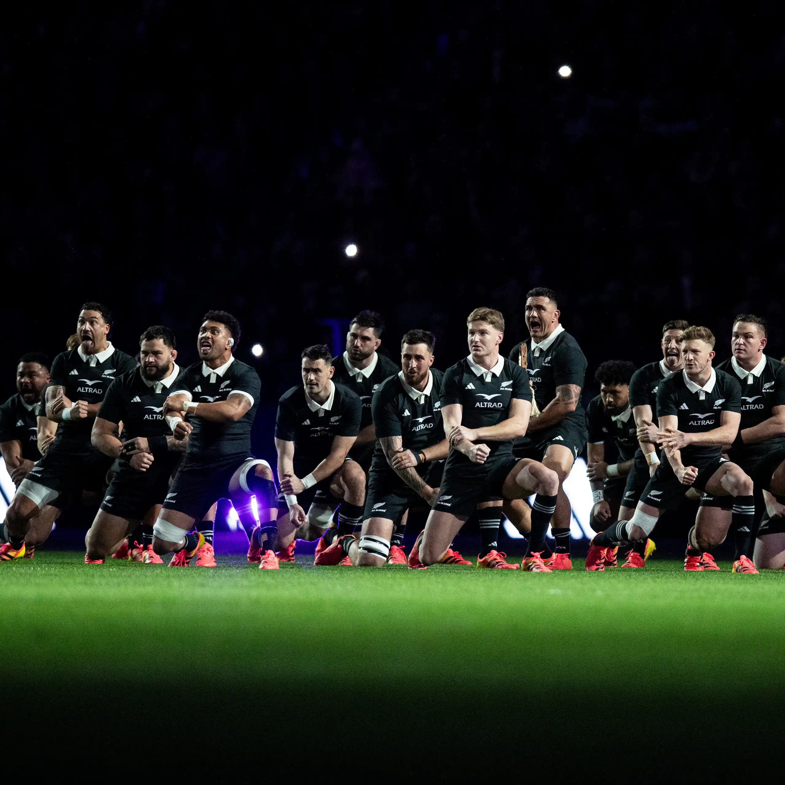 All Blacks team on the field under lights performing the haka