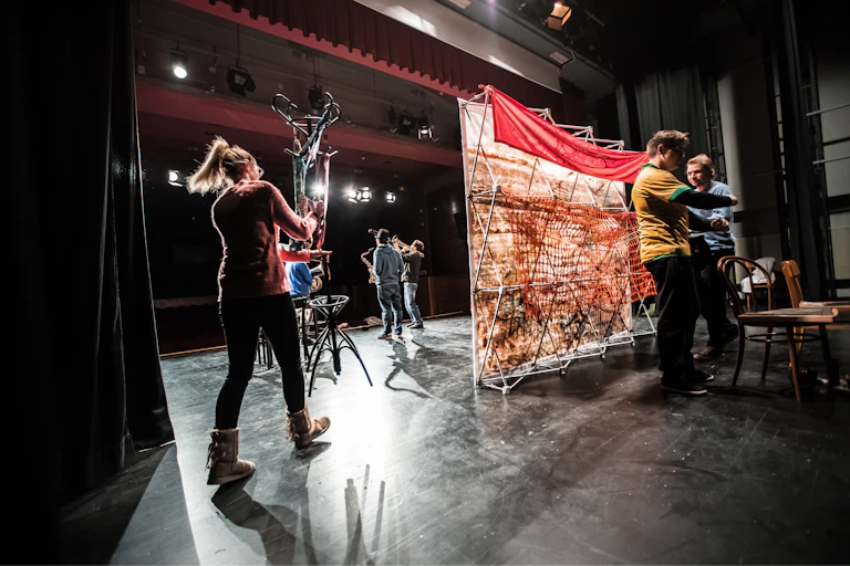 People set up a stage in a theatre.