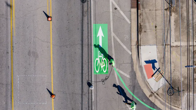 An aerial photo of a person spraying signage on a bike path.