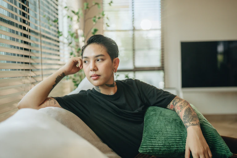 A trans man stares out the window of his livingroom