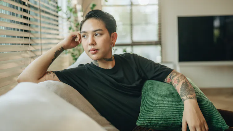 A trans man stares out the window of his livingroom