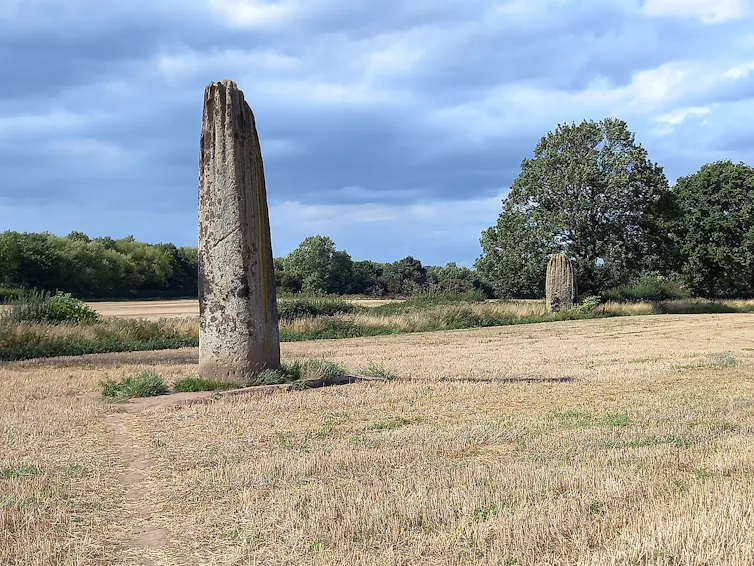A brown field with two large stone pillars jutting into the sky.