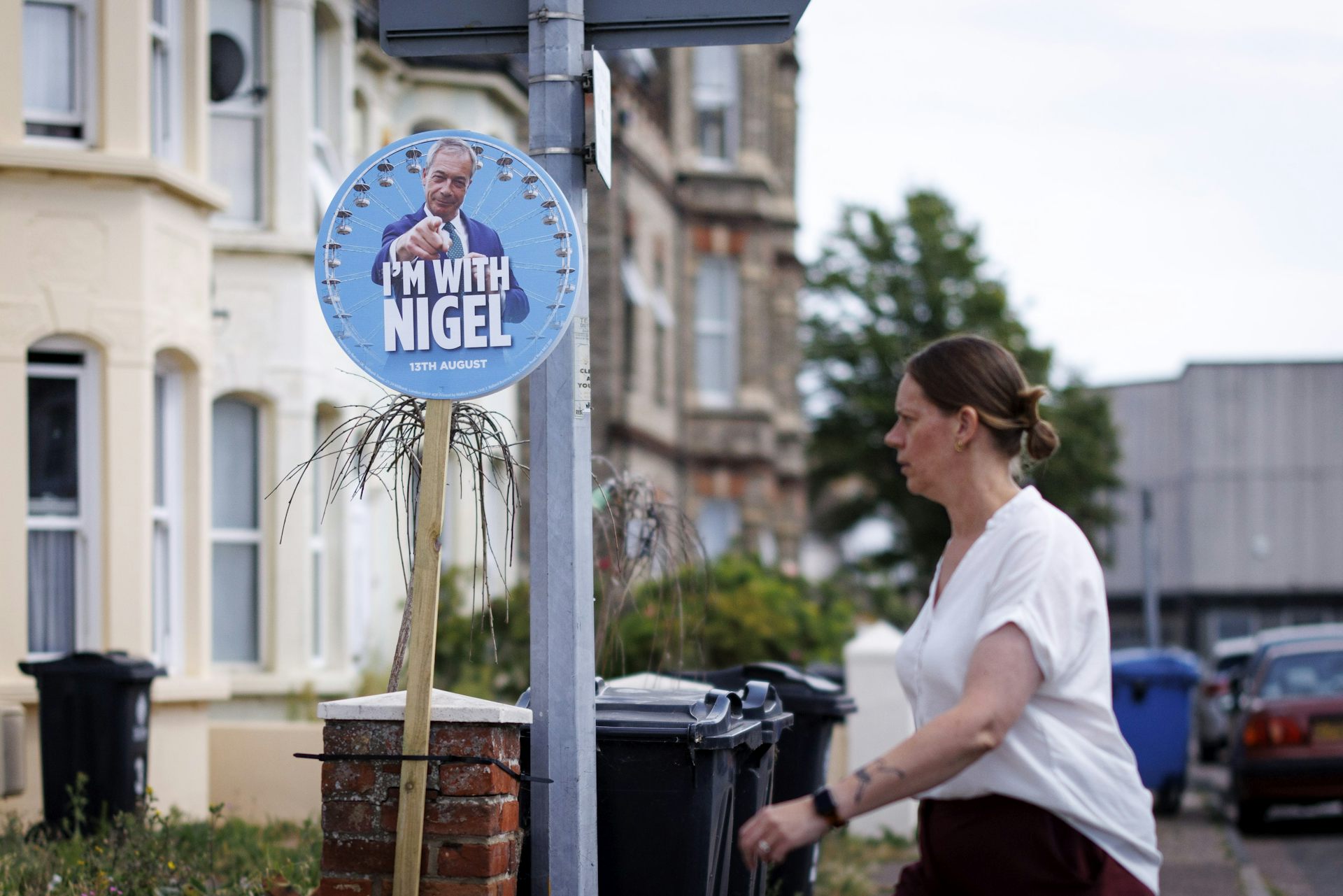 a woman walks past a sign outside a house reading 'i'm with nigel' in the run up to the clacton byelection.
