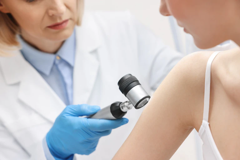 Una doctora examina un brazo de una paciente con un dispositivo óptico