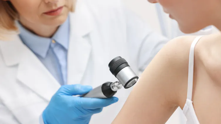 Una doctora examina un brazo de una paciente con un dispositivo óptico