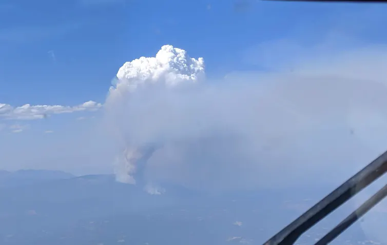 A large smoke plume rises high into the atmosphere