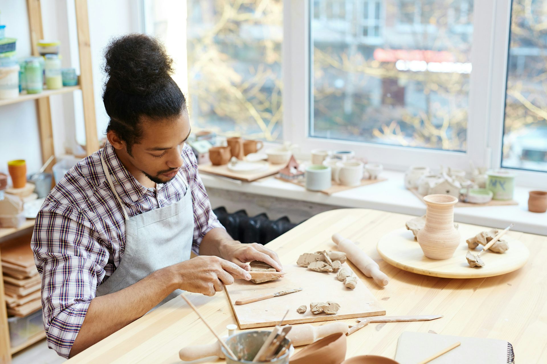 A young man sculpts something out of clay