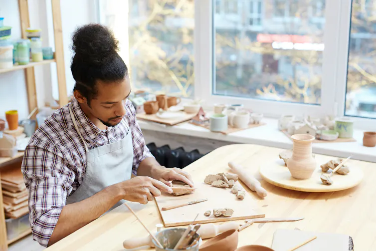 A young man sculpts something out of clay