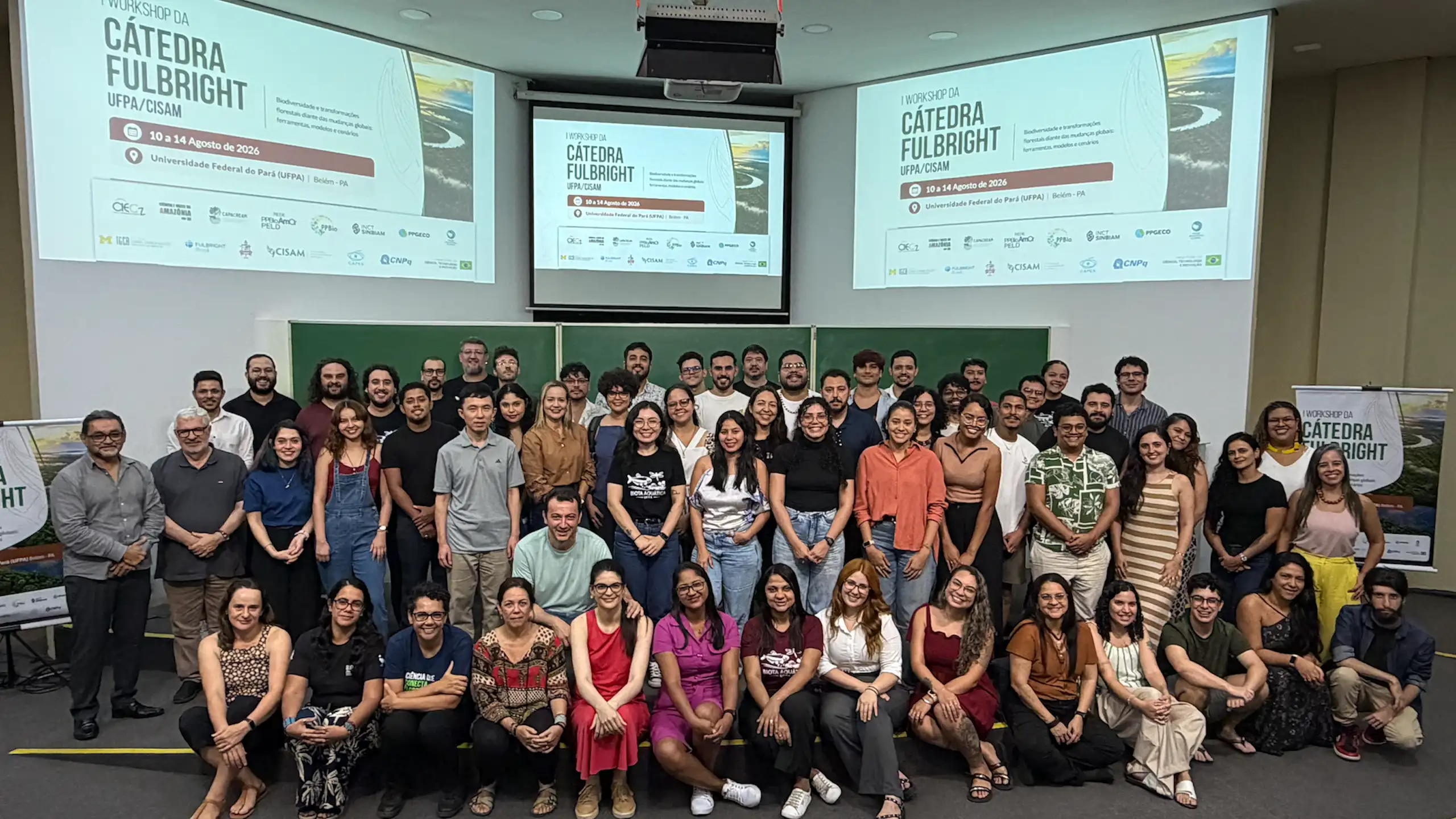 Foto mostra participantes do workshop posando para a foto, com paineis da Cátedra Fullbright ao fundo
