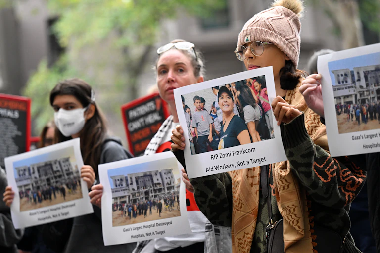 A group of protesters hold signs that say RIP Zomi Frankcom aid workers not a target