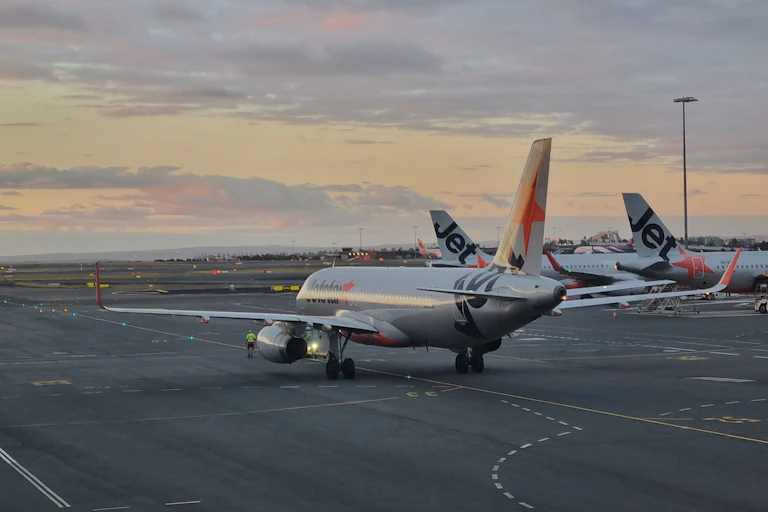 A grey plane on a runway at sunset.