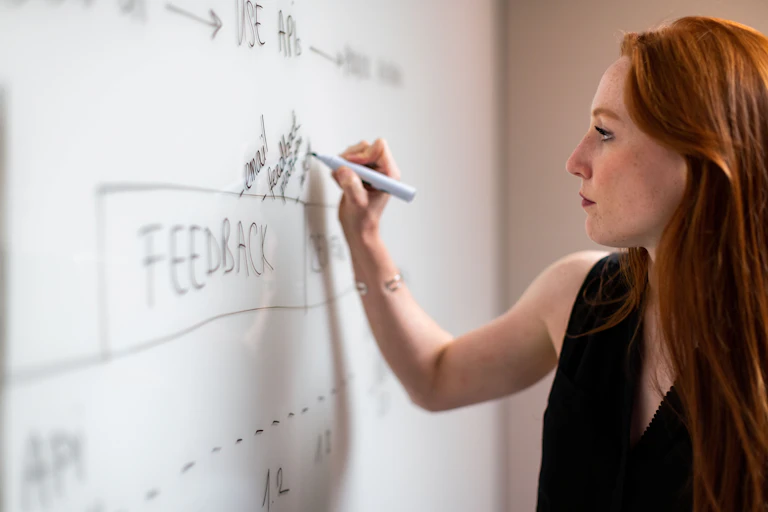 A woman writes on a whiteboard.