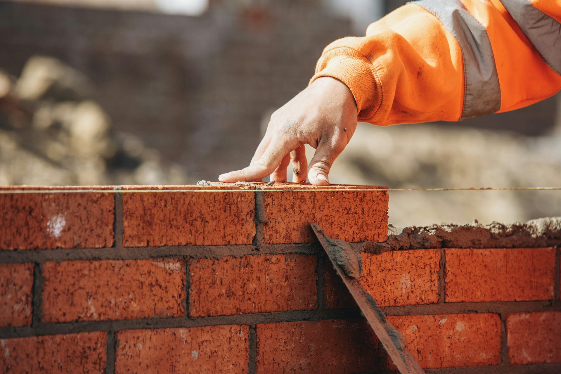 Bricklayer laying another brick in a wall being constructed.