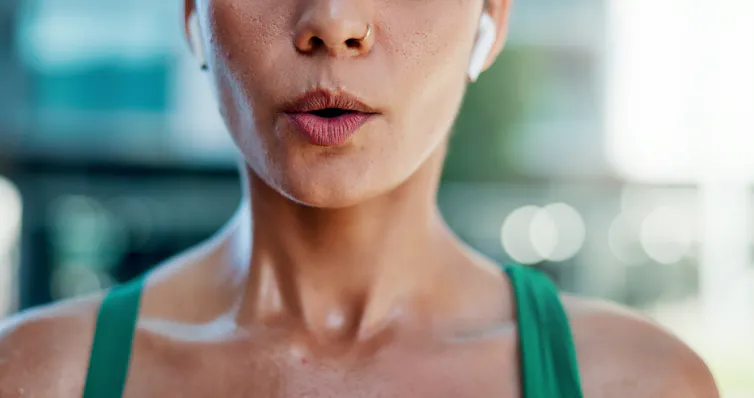 A woman wearing airpods blows out a breath of air.