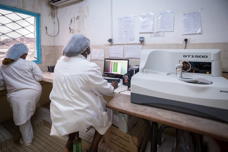 Health workers monitor a screen in a hospital lab