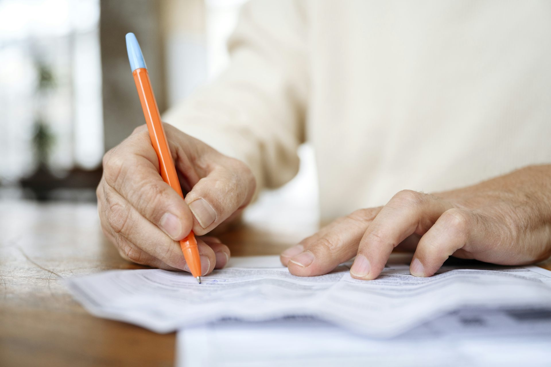 Close up of person holding pen and writing on sheet of paper
