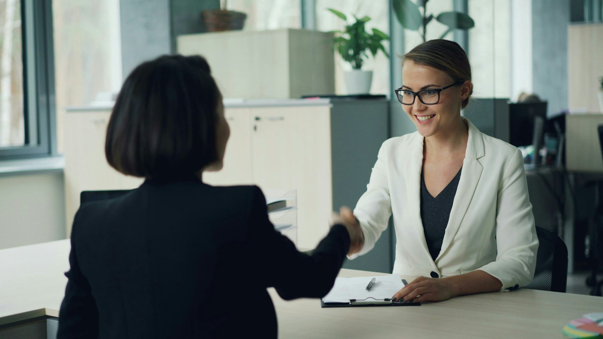 A young woman shakes the hand of an interviewer