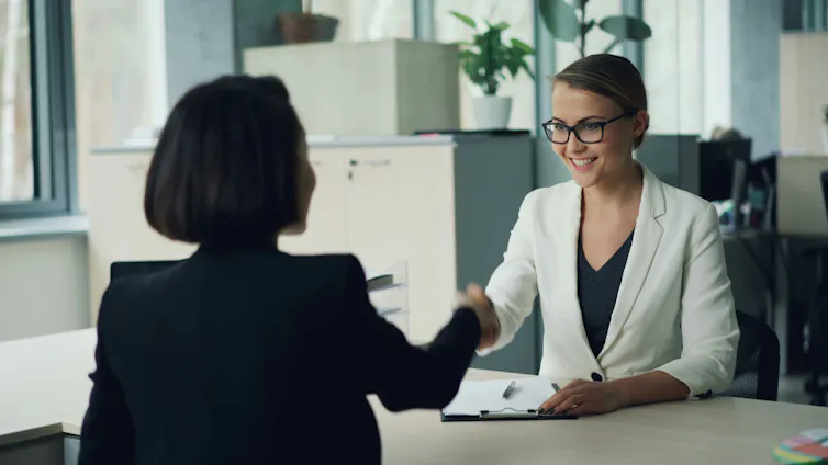 A young woman shakes the hand of an interviewer